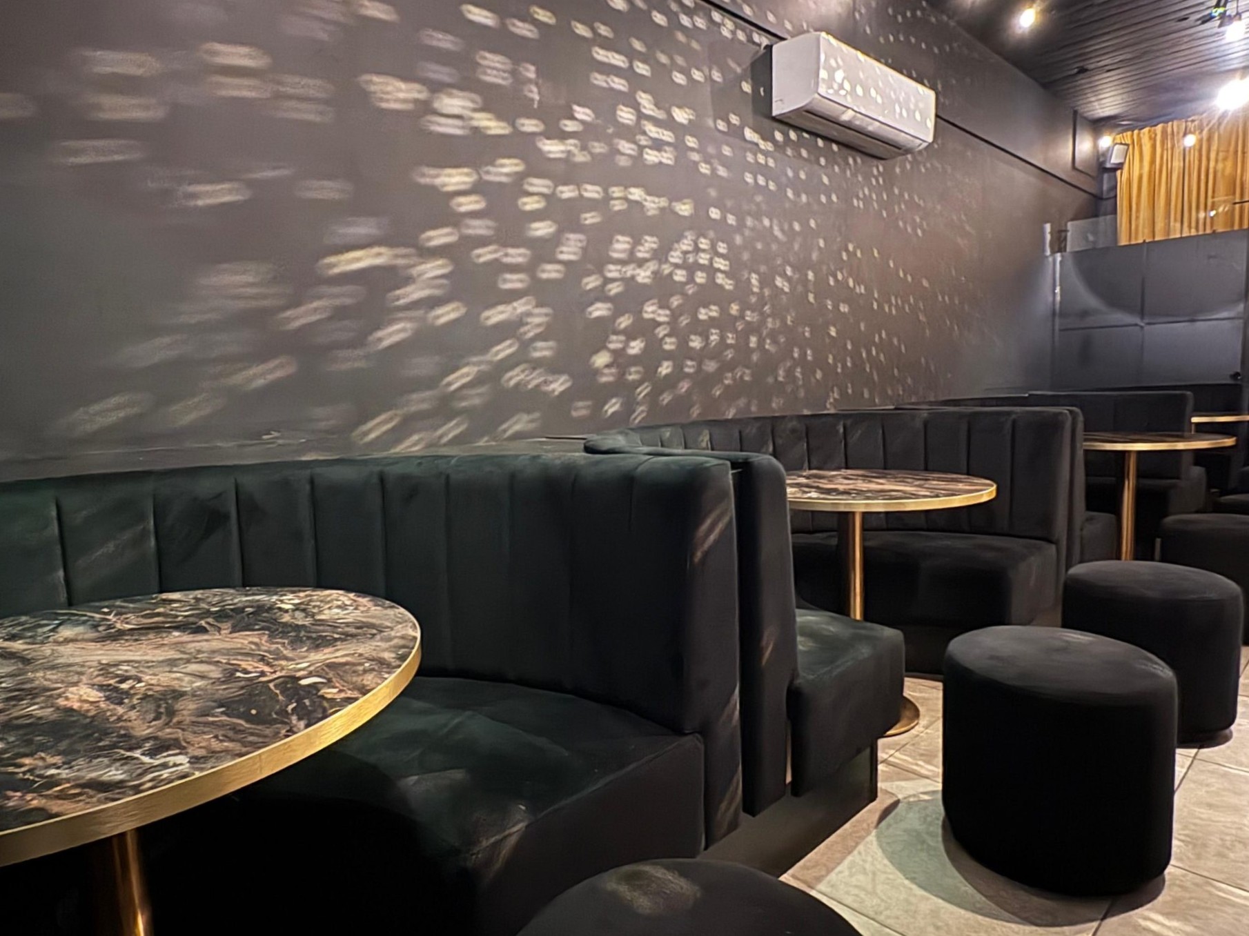 Dark nightclub interior with black upholstered booth seating and round tables