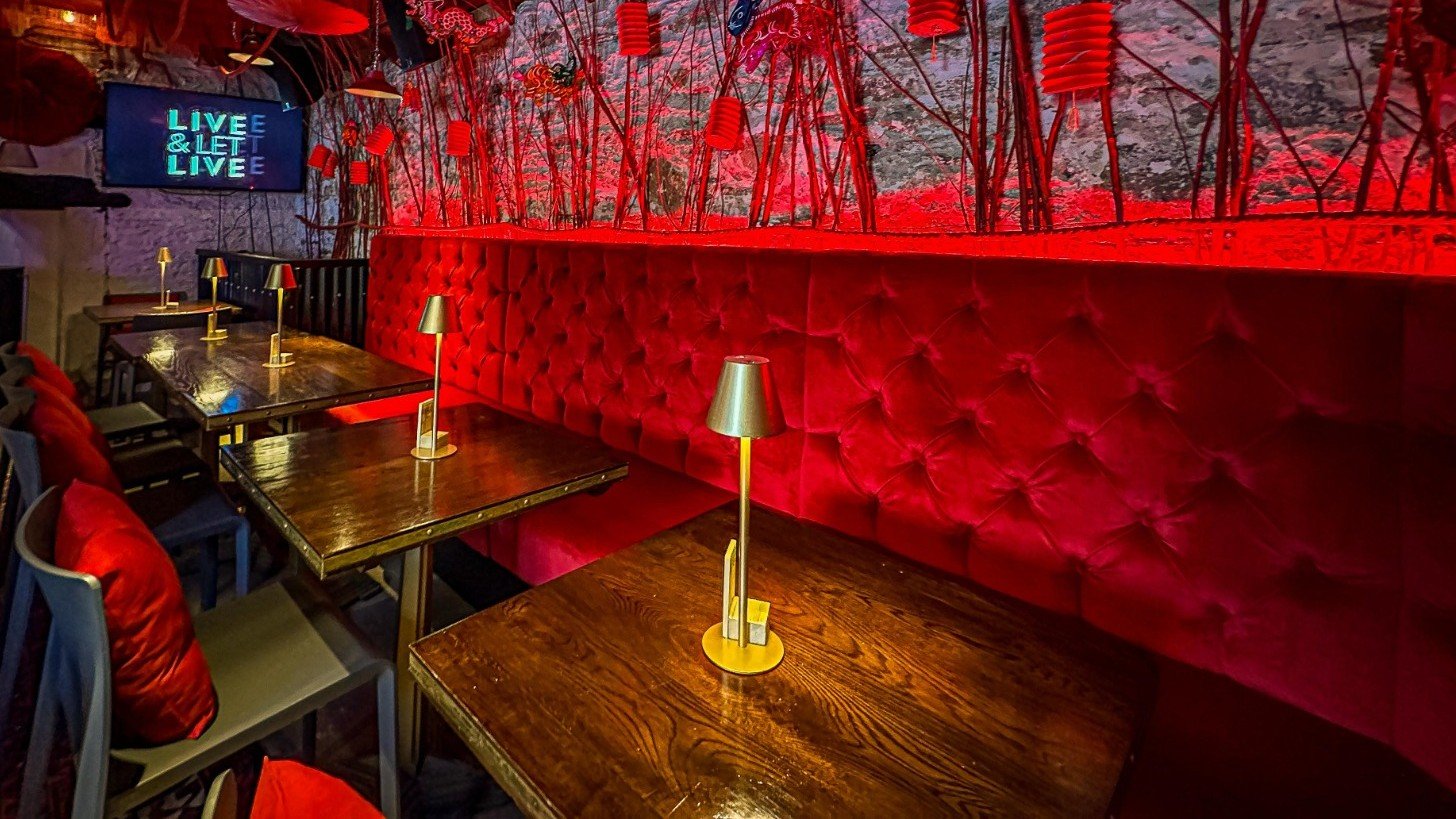 Red buttoned booth seating inside a restaurant with hanging lamps