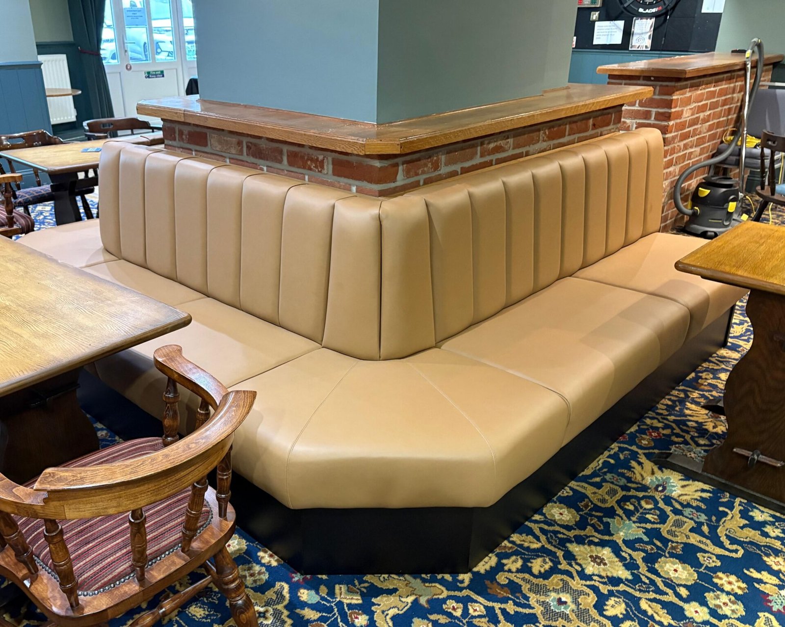Tan fluted banquette built to wrap the brick pillar of a bar counter, with a mitred seat and black plinth.
