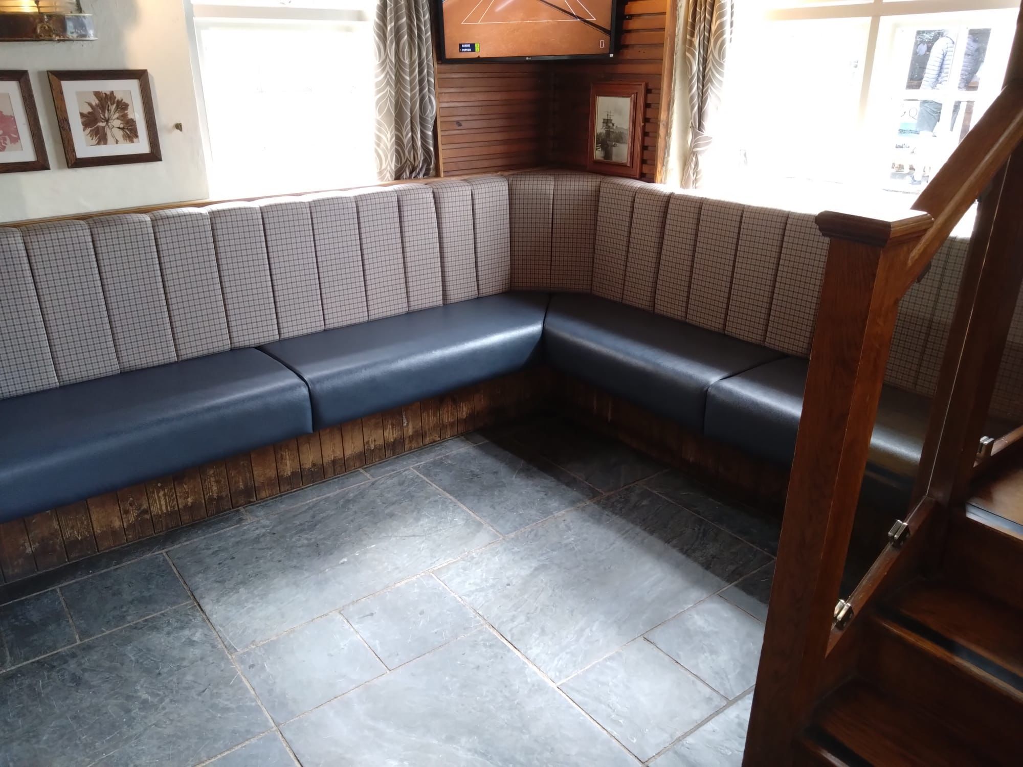 L-shaped pub banquette with a navy leather seat and panelled check fabric backrests fitted into a window corner.